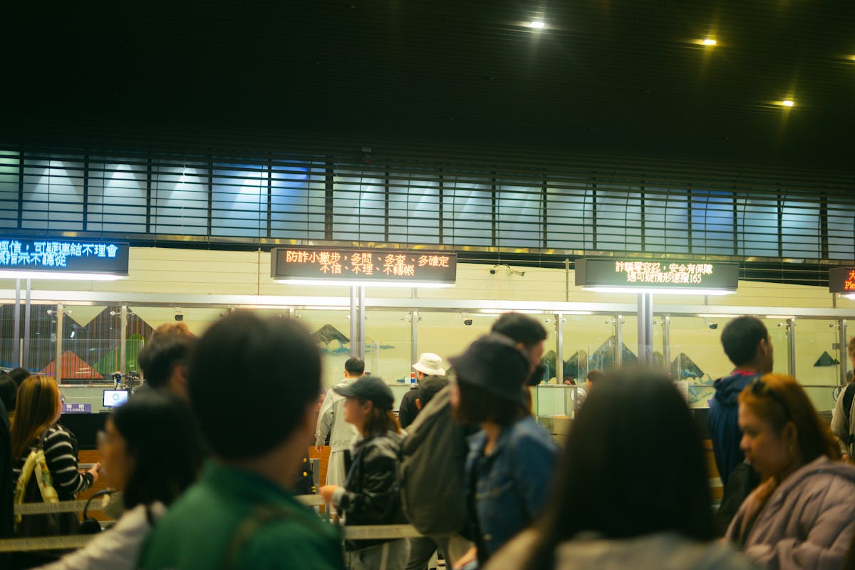 Crowded airport check-in area with people queueing and flight information signs