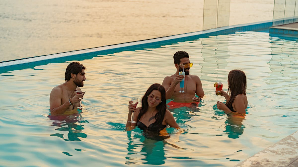 Adults socializing and enjoying drinks in hotel pool at sunset – weekend takeover schedule lifestyle hotel Europe