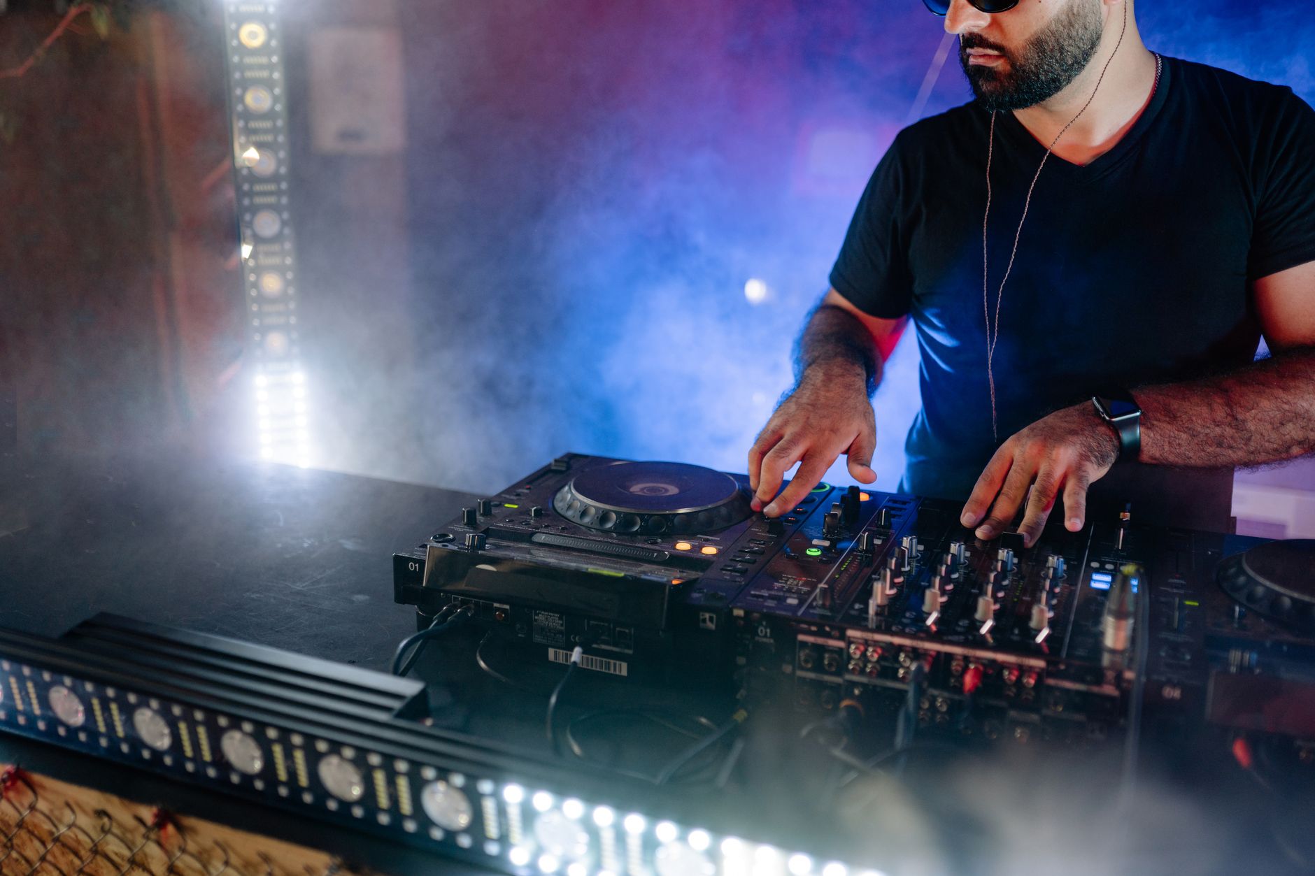 DJ mixing tracks behind the decks in a smoky nightclub with blue and red lights β best clubs and nightlife in Tenerife 2026