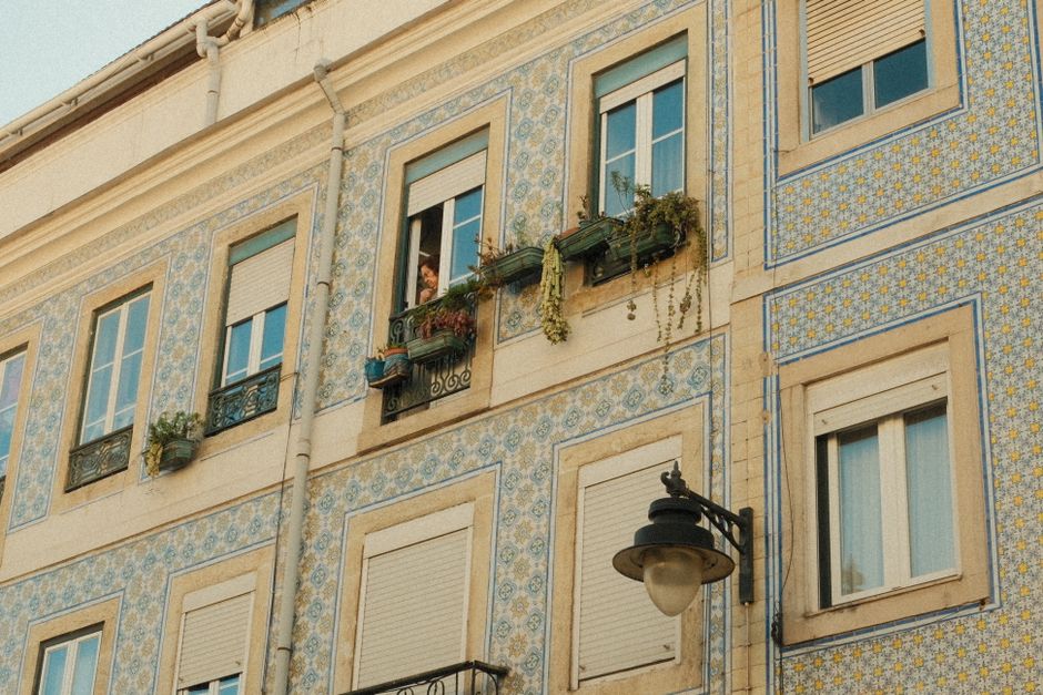 Historic Lisbon facade with azulejos tiles and a person looking out. Captures Portuguese architectural charm. – The Best Budget Hostels in Lisbon (Named)