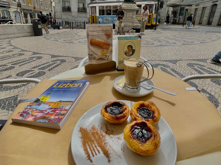 Savoring Pastéis de Nata with coffee in a Lisbon café, with iconic tram in the backdrop. – How Much Do Lisbon Hostels Actually Cost in 2026?