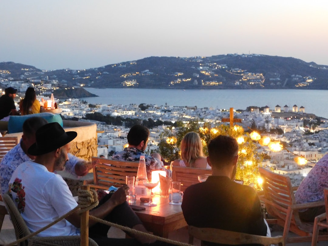 people sitting on chair in front of table with candles on top of it during night – What is a night out in Mykonos actually like?
