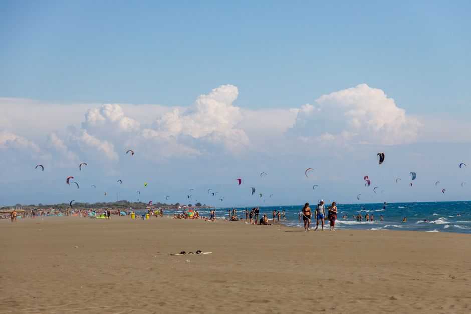 Vibrant scene of people and kitesurfers enjoying Ulcinj's sandy beach under a clear summer sky. – When and Where Is EXIT 2026 Exactly?