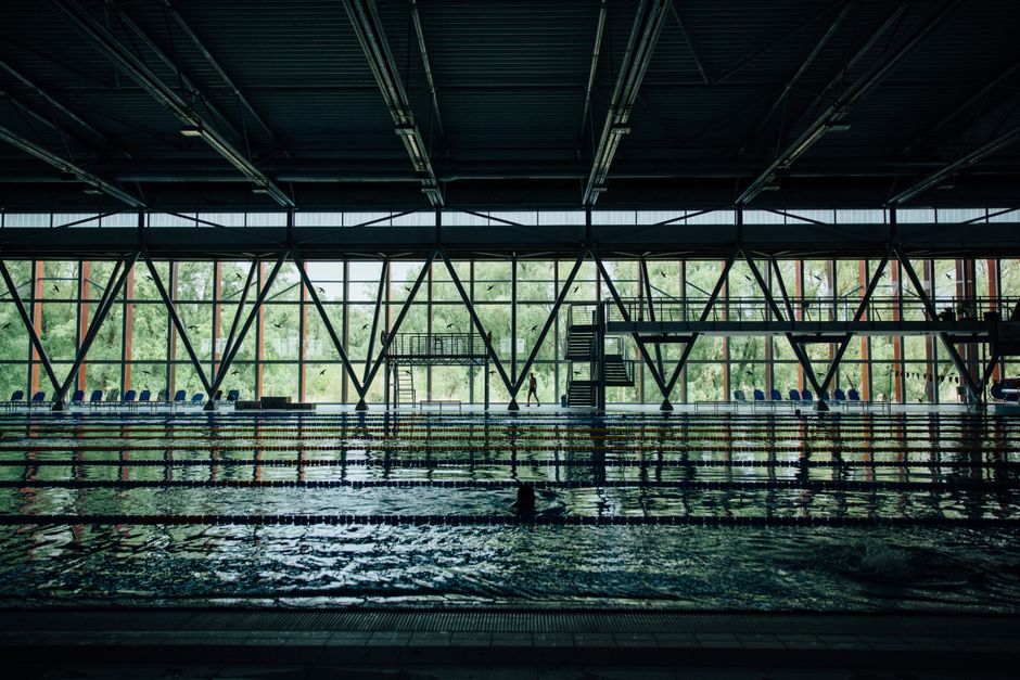 Unrecognizable sportsman silhouette strolling between decorative wall and swimming pool with rippled water and floating markers – What to Expect on Your First V