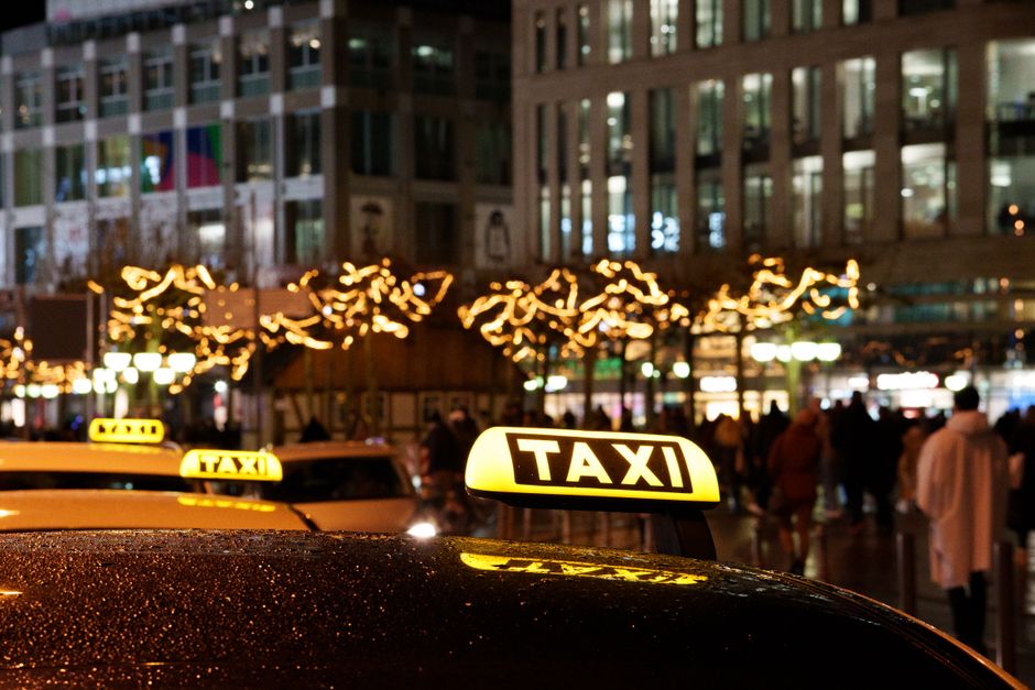 A vibrant city scene at night featuring taxis with illuminated signs and festive decorations. – Staying Safe, Legal and Getting There