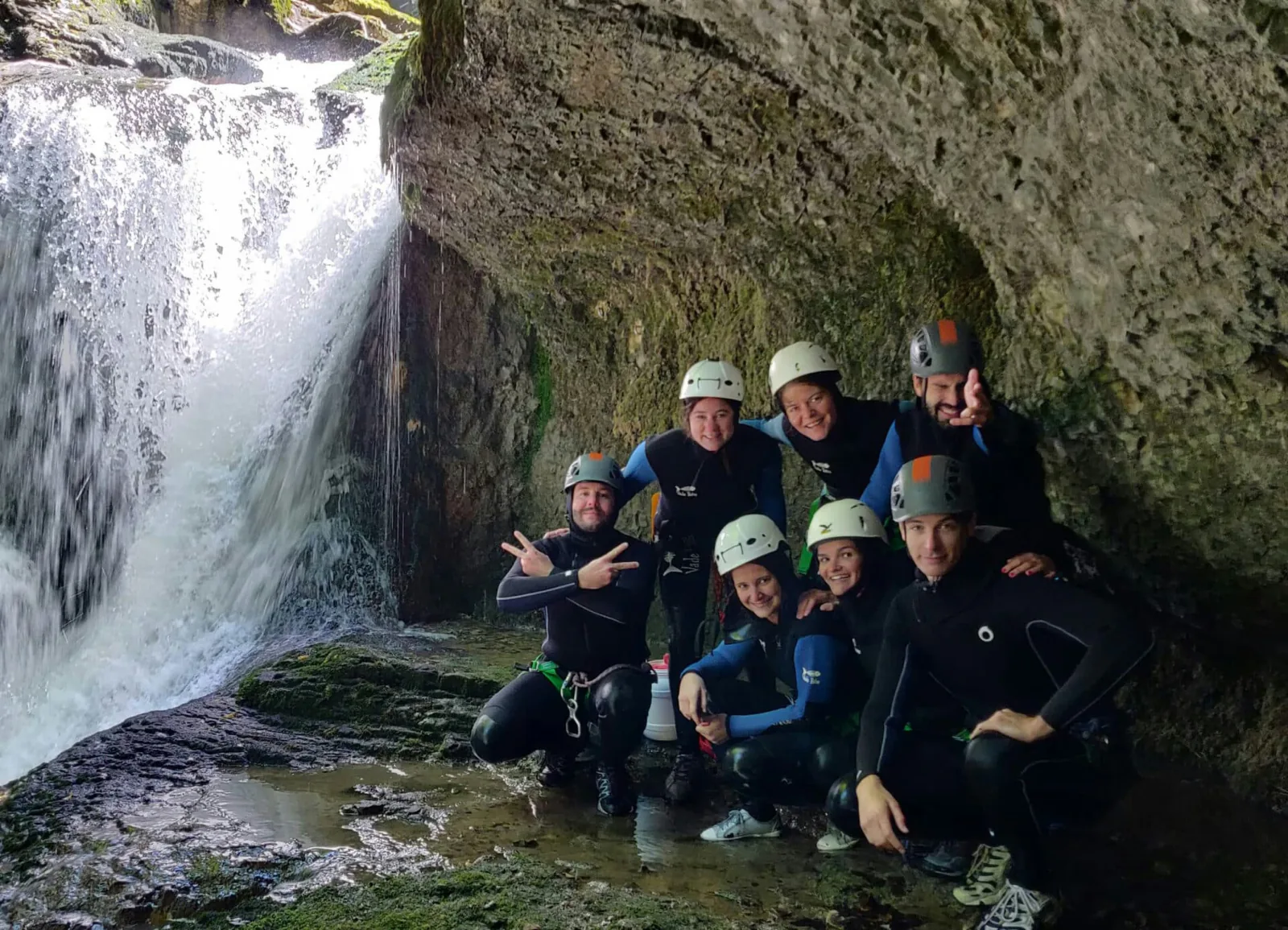 What a canyoning trip includes for the price: a small guided group in wetsuits and helmets moving through a canyon with