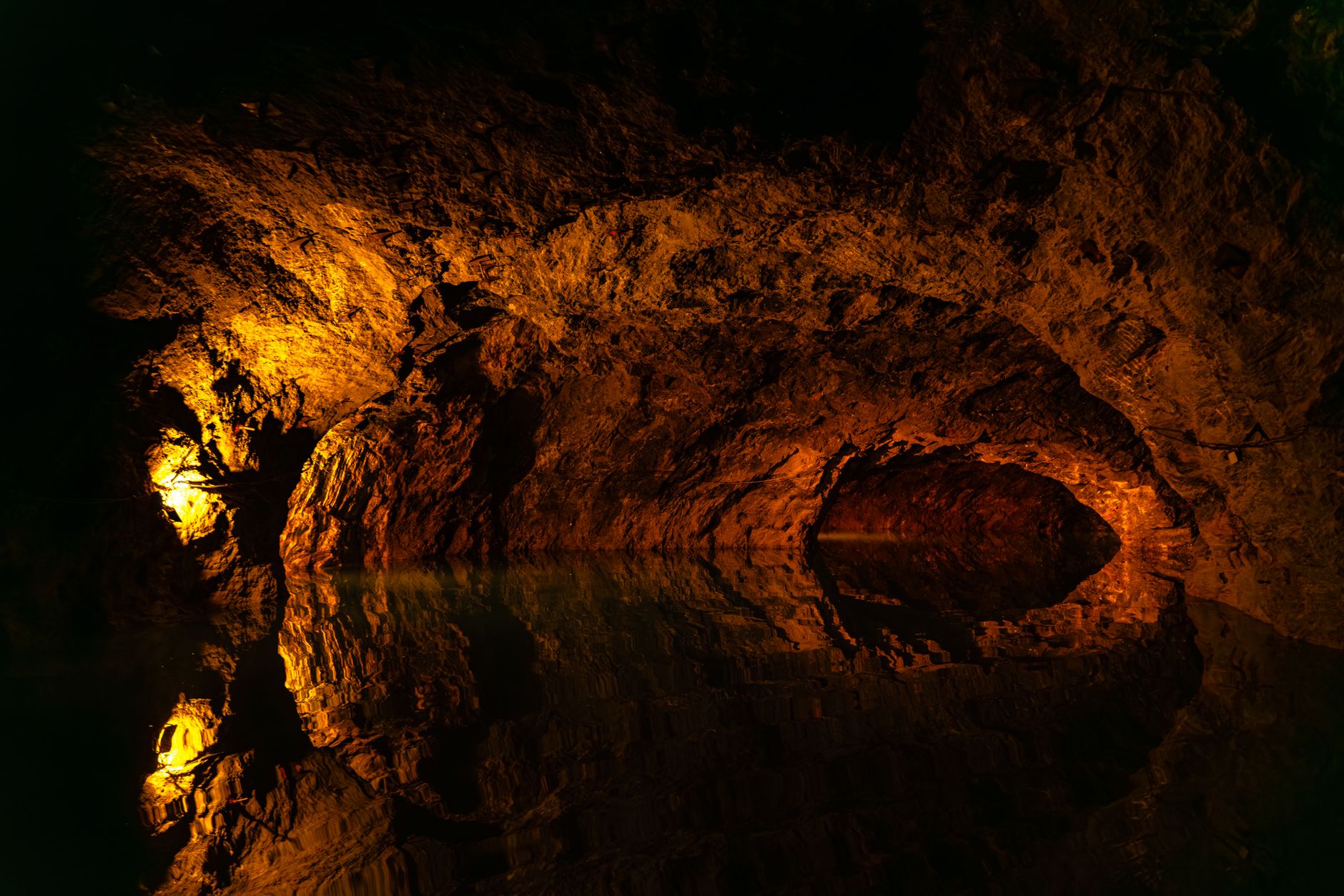 Križna Cave's still, dark underground lakes crossed by small wooden rowboat, headlamp-lit