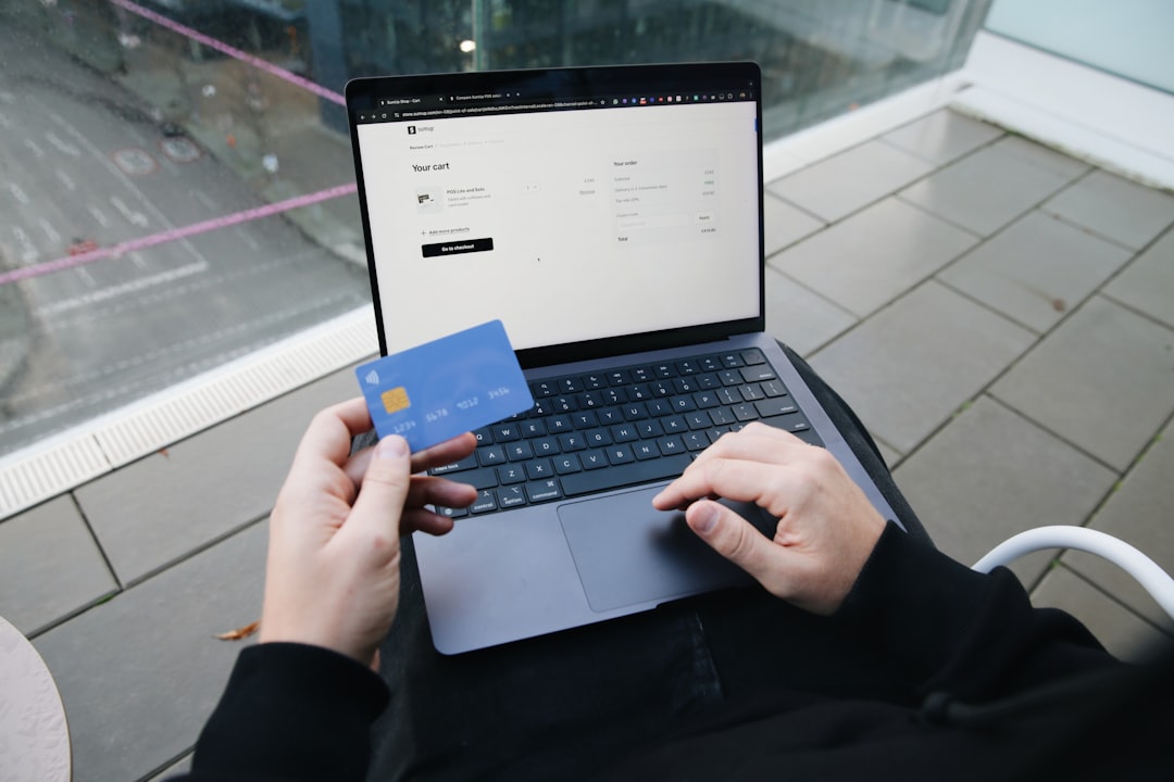 A person sitting in a chair with a laptop and a credit card – How Big Are Sign-Up Bonuses, and How Do You Hit Them?