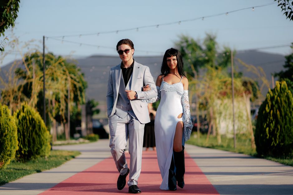 Stylish couple walking confidently on red carpet outdoors in elegant fashion. – Dress Codes, Entry Rules, and Couples-Only Policies