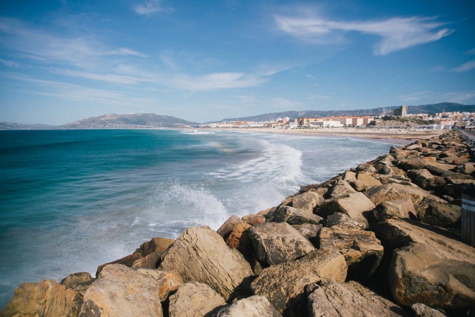 Picturesque scenery of turquoise bay of sea washing rocky coast against blue sky with rare clouds near small town on sunny day – Getting to Tarifa: Flights, Tra