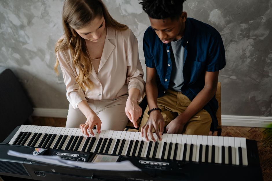 Teenager learning piano with an adult teacher, capturing an intimate musical moment. – What to Expect From Your First Lesson