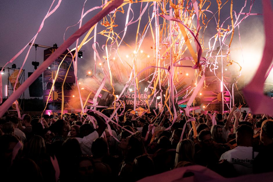 Crowd enjoying a vibrant festival with colorful ribbons and stage lights under a twilight sky. – What Is Awakenings Festival, Exactly?