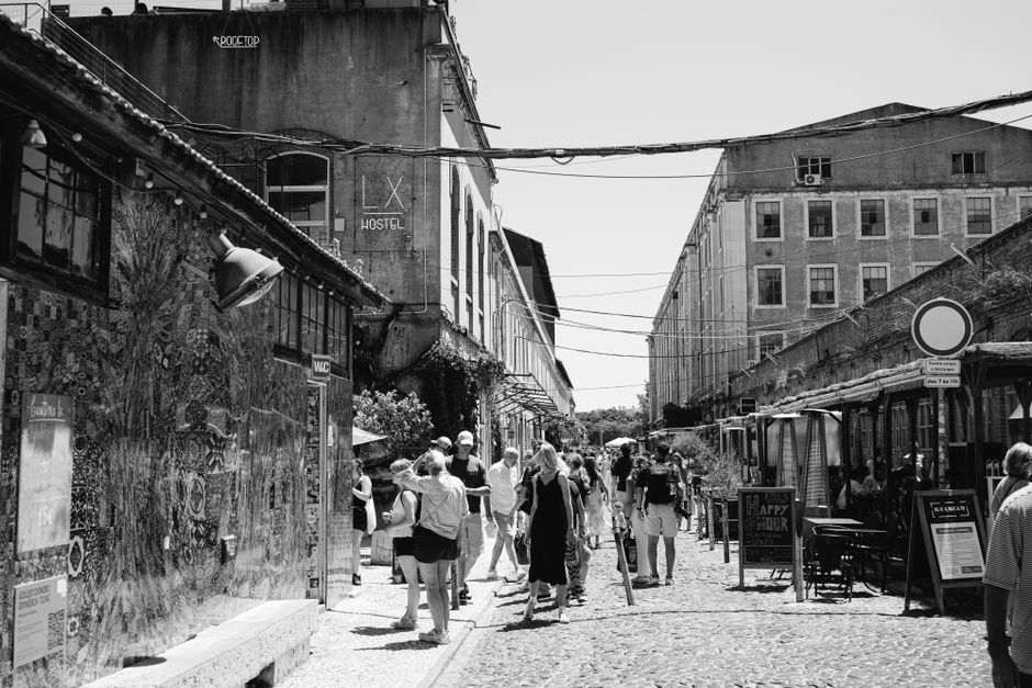Black and white photo of people exploring the vibrant streets of LX Factory, Lisbon. – Getting from Lisbon Airport to Your Hostel