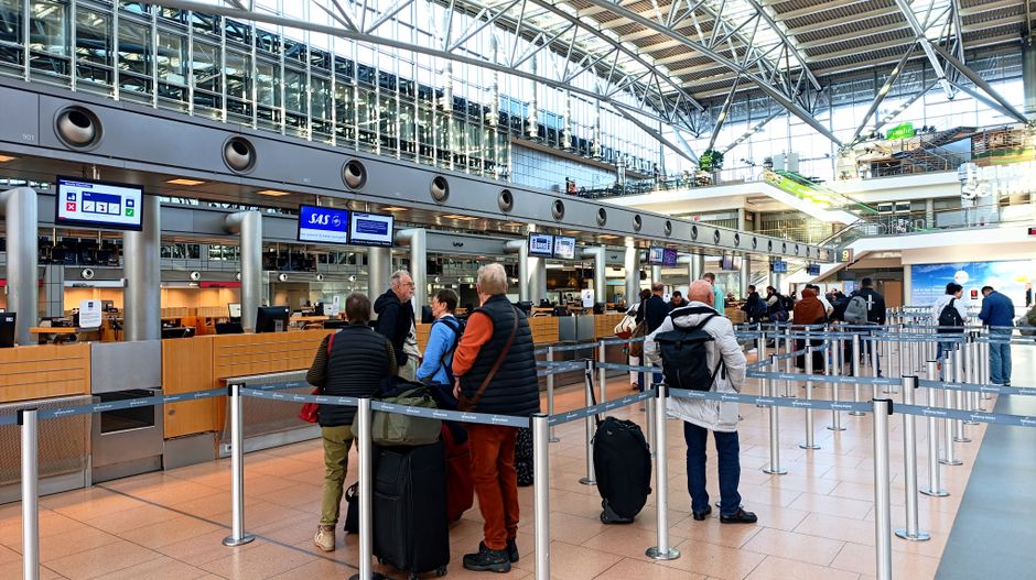 Travelers in line at Hamburg Airport's check-in counters, showcasing modern architecture. – How Far in Advance Should You Book Flights to Europe?