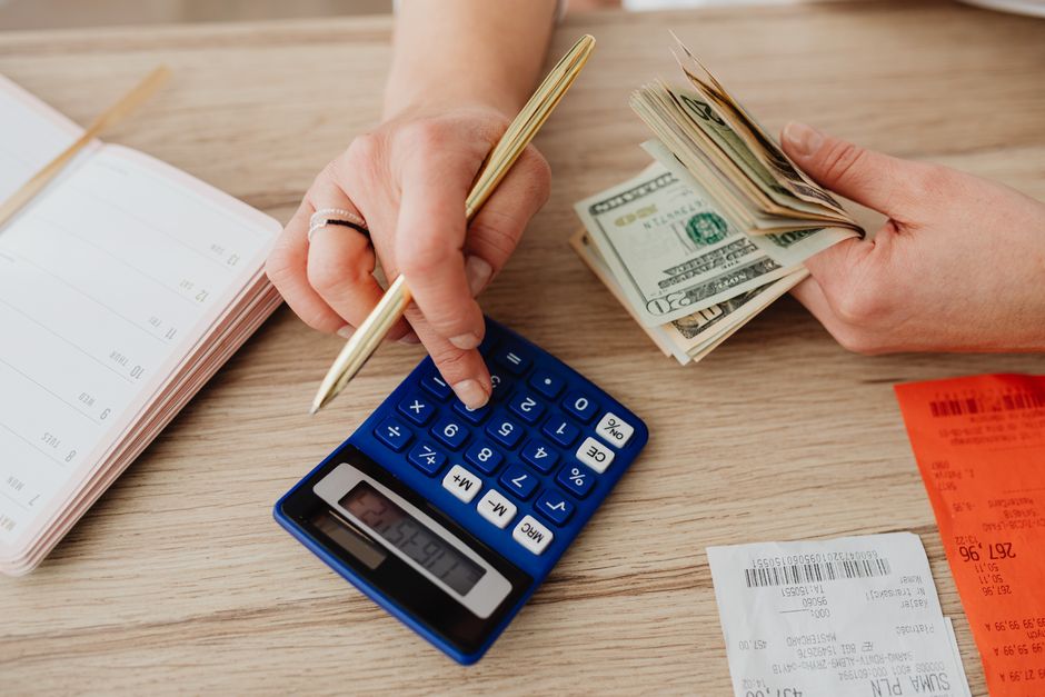 Hands handling cash and calculator for budget planning. Modern financial scene. – Tools and Tricks That Actually Save Money in 2026