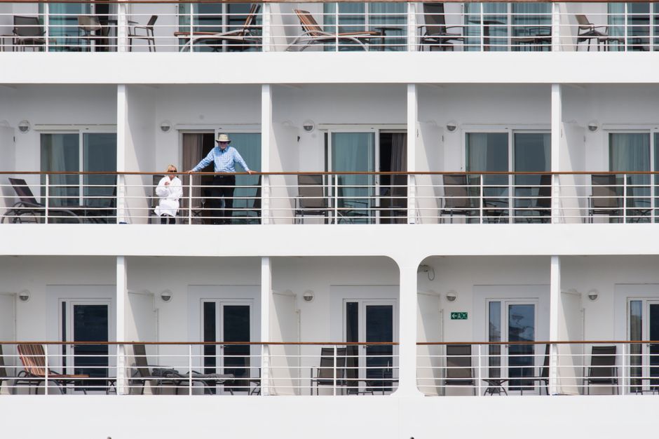 A couple enjoys leisure time on a cruise ship balcony, with smooth architecture. – Saga and Ambassador: Britain's 50+ Adults-Only Duo