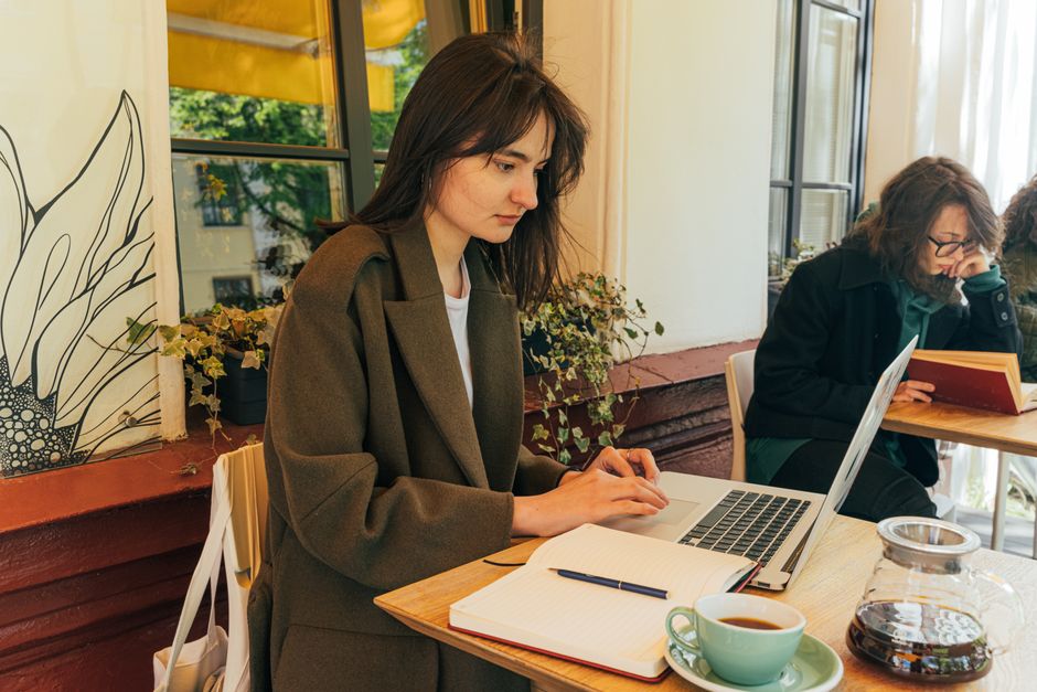 Woman using a laptop in a sunlit cafΓ©, enjoying a coffee and working diligently. β 5. Toggle Between "Cheapest" and "Best" β They're Not the Same List