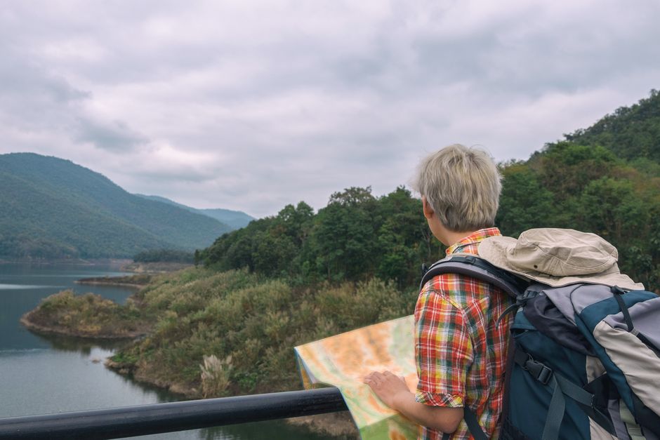Traveler with backpack and map exploring picturesque mountain landscape. – Independent vs Guided: Total Cost Breakdown