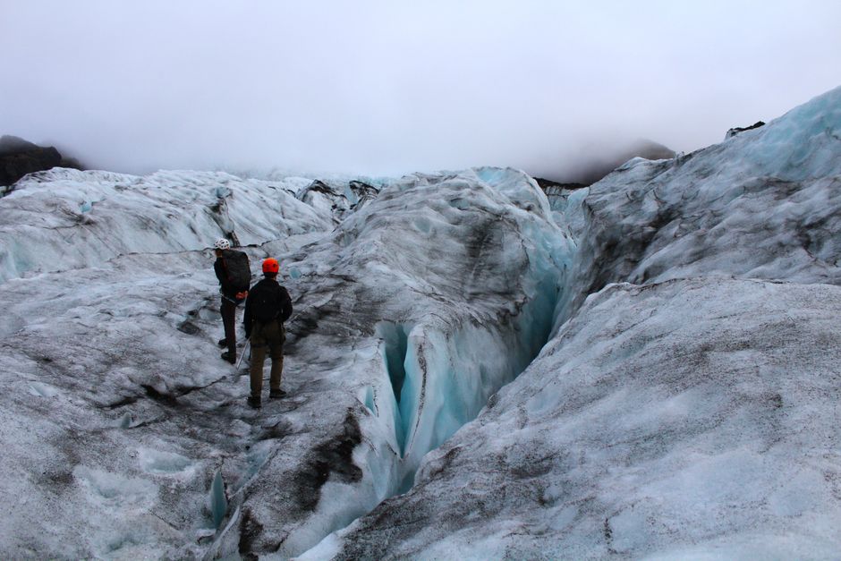 Two adventurers explore a glacial landscape in Iceland, experiencing the raw beauty of nature. – Sólheimajökull vs. Skaftafell vs. Vatnajökull: Picking Your Gla