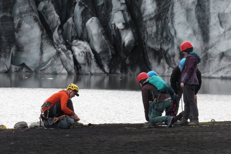 Guide fitting crampon harnesses for a group at a black-sand glacier lagoon, Iceland – Guided Only: Why You Can’t Just Walk Onto an Icelandic Glacier