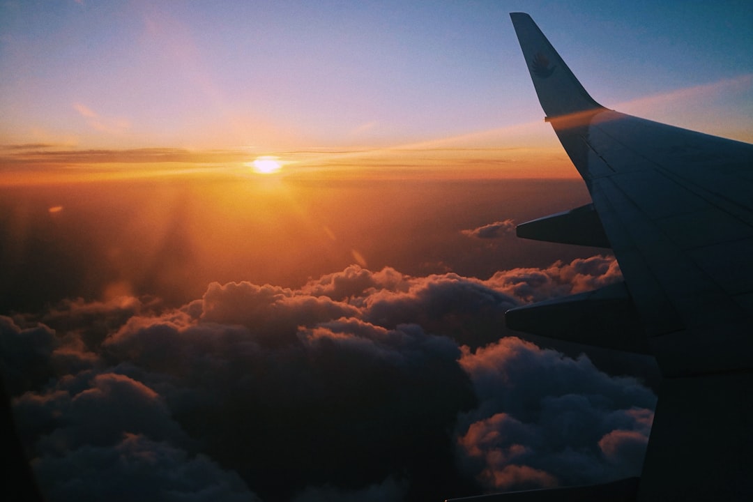 airplane over clouds during golden hour – Is There Really a Cheapest Day of the Week to Fly?