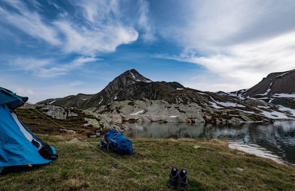 Scenic mountain landscape with tent setup by a tranquil lake, ideal for adventure seekers. – Gear Checklist: What to Pack