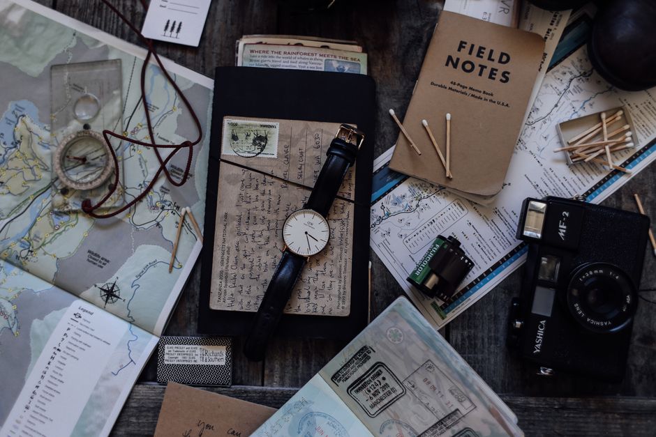 Top view of vintage photo camera near wristwatch and camera roll near maps and notebook near compass and papers near matches placed on table – Permits and Paper