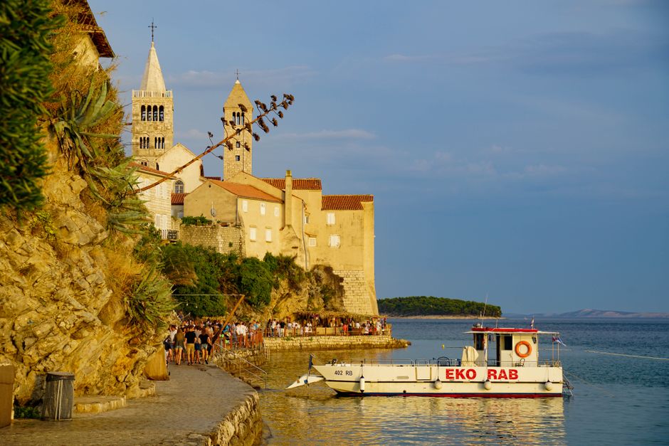 Eko Rab boat docked at Rab Island's historic waterfront with medieval architecture, a popular tourist spot. – Rab Island: Where European Naturism Began