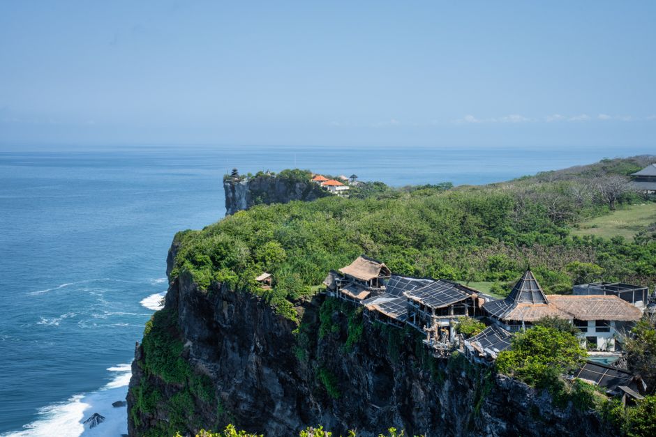 A breathtaking view of Uluwatu's cliffside with ocean and traditional huts, Bali. – Uluwatu: Clifftop Villas Built for Privacy
