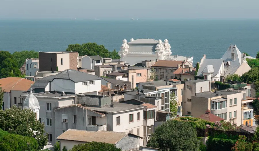 A picturesque view of a coastal town with Mediterranean-style architecture by the sea. – How to Get to Costinești From Abroad