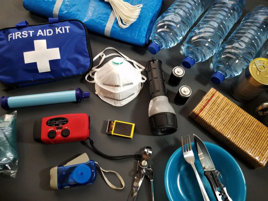 Flat lay of essential emergency survival kit items including first aid and water bottles. – First-Timer Survival Tips