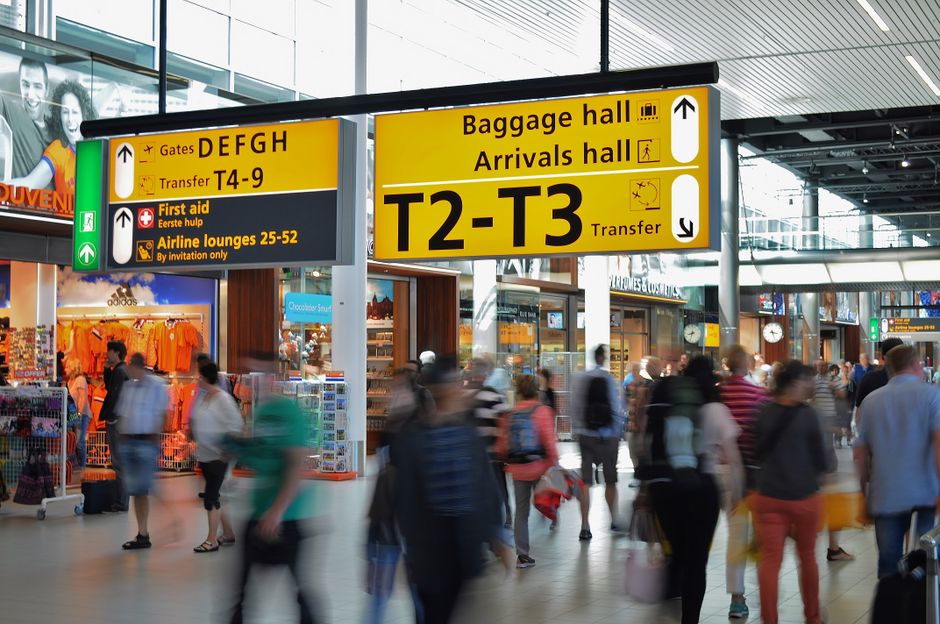 Crowded airport with motion blur and clear signage indicating baggage and arrival halls. – Getting There: Flights, Transfers and Where to Stay