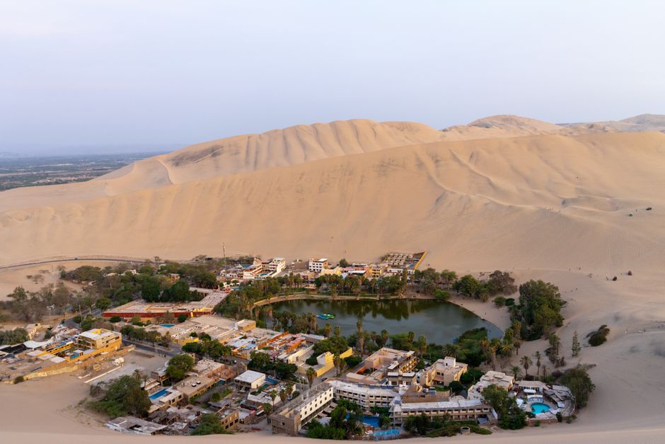 A breathtaking aerial view of the Huacachina oasis surrounded by sand dunes in Ica, Peru. – Where Is Huacachina and How Do You Get There?