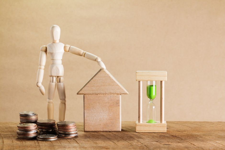 Wooden mannequin with house model, coins, and hourglass symbolizing financial planning. – Costs, Timing, and Booking