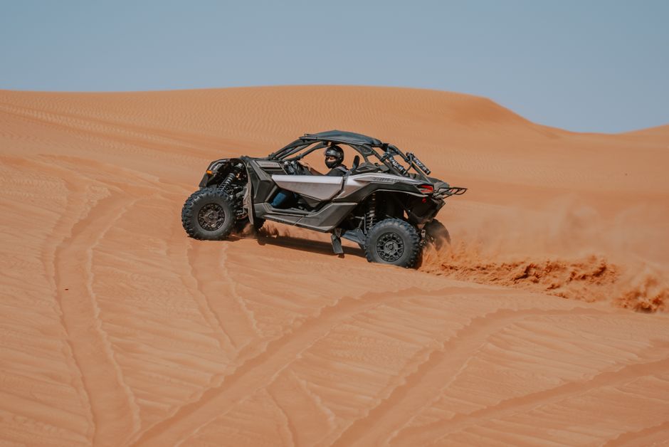 Dynamic capture of an ATV navigating through desert sand dunes under a clear sky. – Ready to Book Your Dune Adventure?