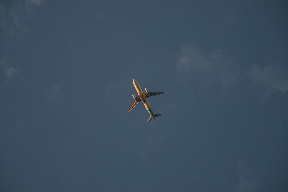 A passenger airplane flies across a clear twilight sky, symbolizing travel and freedom. – Getting to Boomland: Flights, Shuttles, and the Journey In