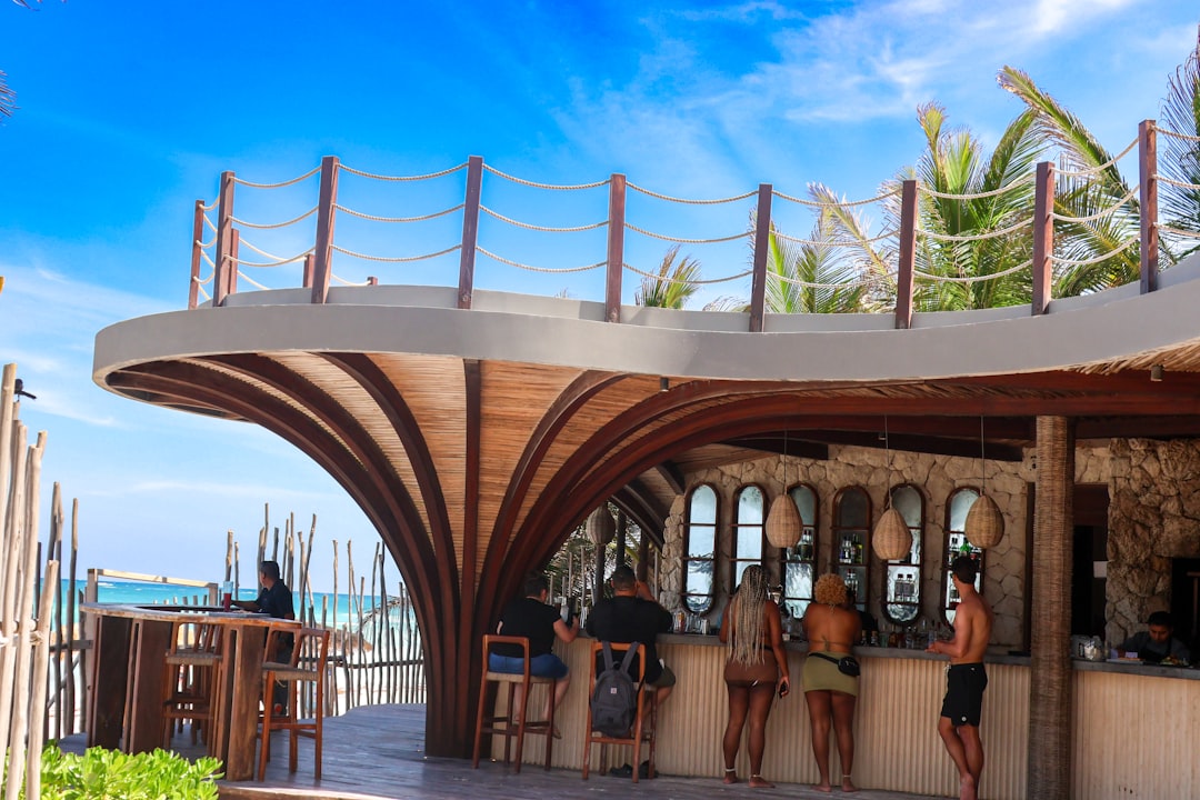 a group of people sitting at a bar next to the ocean – What to Wear and Bring to Zamna Tulum