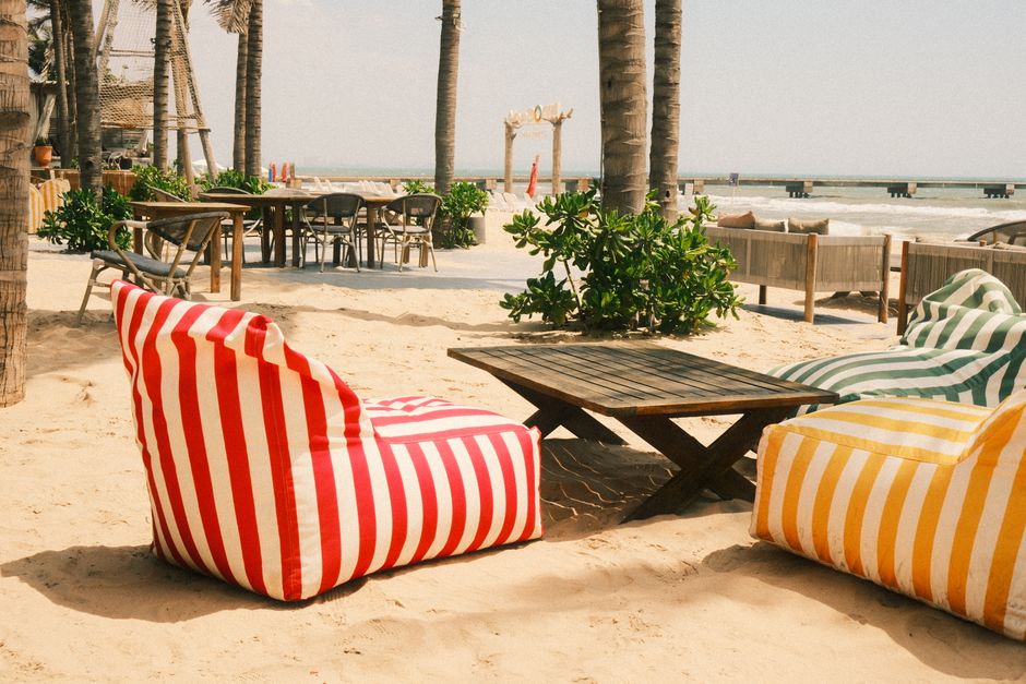 Cozy beach lounge in Phan Thiet, Vietnam with striped bean bags and palm trees. – Zamna Tulum vs Tulum's Other Beach Day Parties