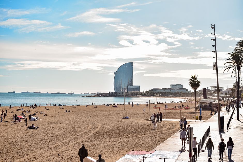 A vibrant day at Barceloneta Beach, showcasing the iconic W Hotel and lively atmosphere. – How Do You Actually Qualify for One?