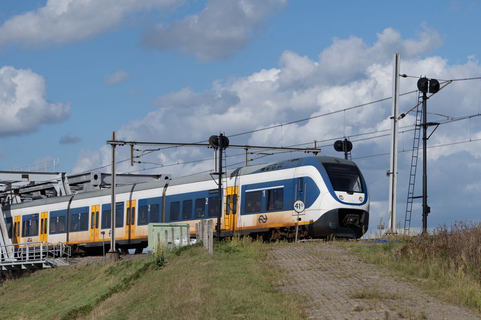 A sleek train travels on elevated tracks through rural landscape under a blue sky. – Getting to Biddinghuizen From Abroad