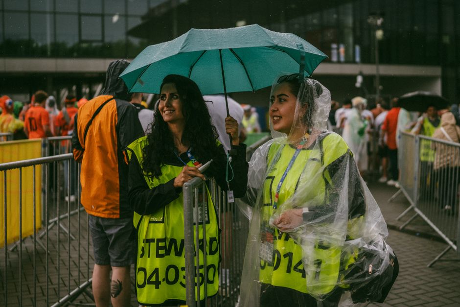 Two female stewards smiling under an umbrella at an outdoor event in rainy weather – Frequently Asked Questions