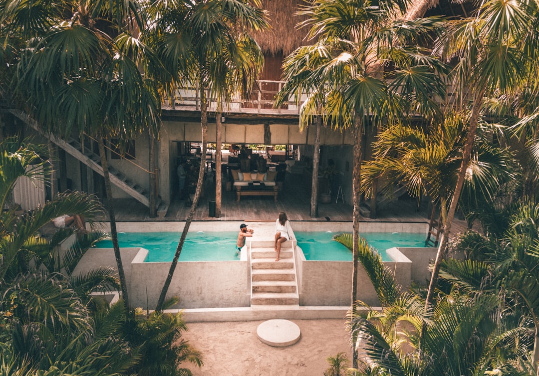 man and woman swimming at pool surrounded by trees – What Is Zamna Tulum? Inside the Jungle's Biggest Pool Party