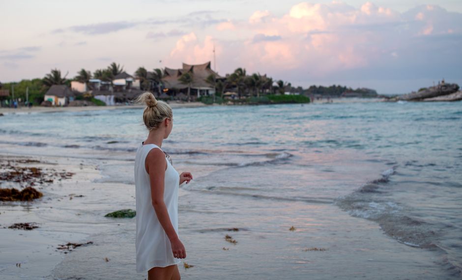 Woman in white dress enjoying sunset at Tulum beach, Mexico. Serene coastal landscape. – What to Wear and Bring to Zamna Tulum