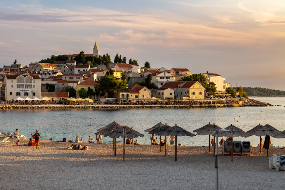 Beautiful beach scene with town and umbrellas at sunset in Primošten, Croatia. – Is Nude Sunbathing Legal in Croatia?