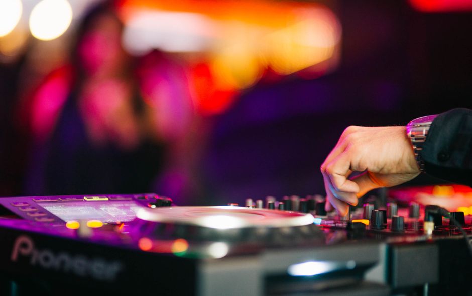 Hand of DJ mixing music on turntable at a lively nightclub event – Music Styles: Finding Your Perfect Club