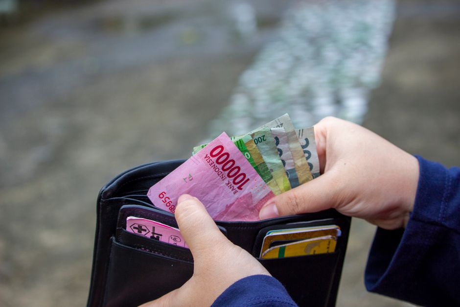 Close-up of hands managing banknotes, focusing on Indonesian Rupiah and diverse currencies – 2026 Pricing: What You'll Actually Pay