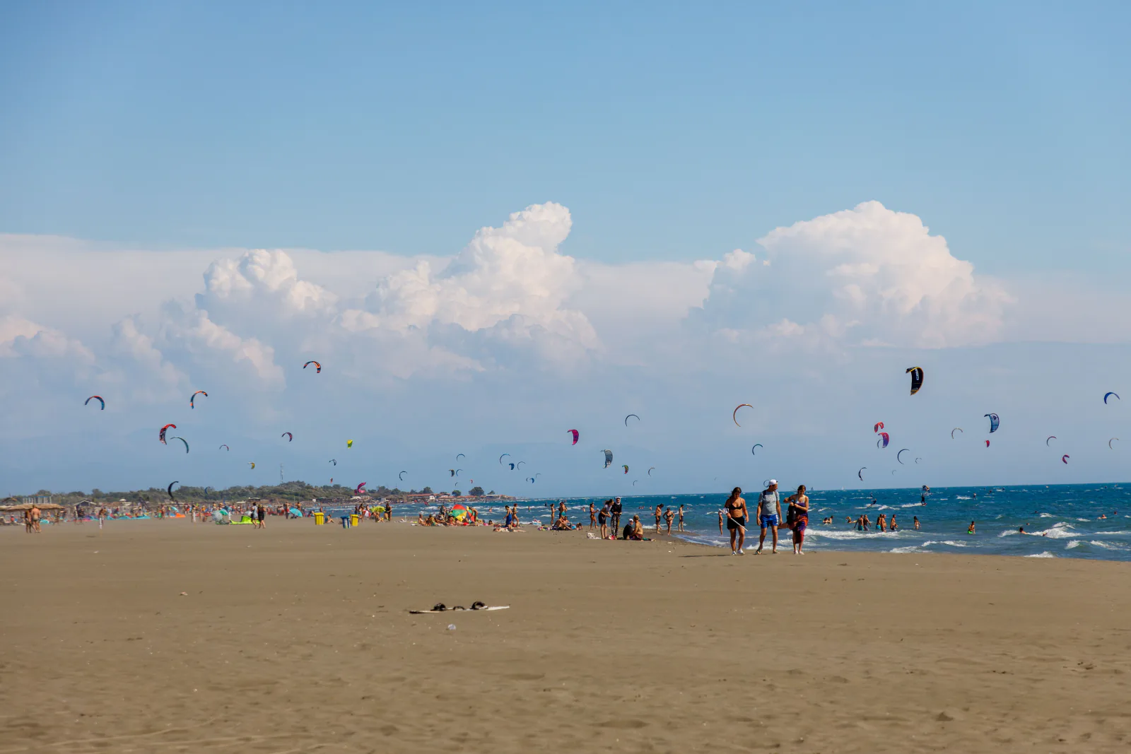 Kitesurfers and beachgoers filling Ulcinj's sandy shoreline under a summer sky – What's the Lineup and Vibe Like in Montenegro?