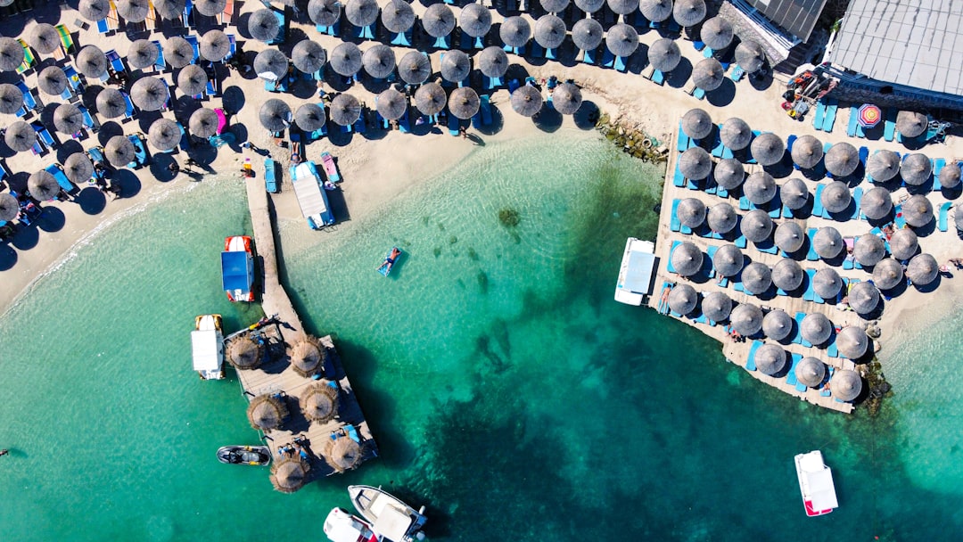 an aerial view of a beach with umbrellas and boats – Why Ksamil Became Albania's Beach Club Capital
