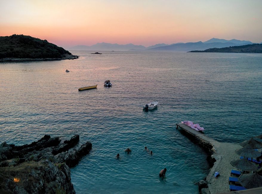 Golden sunset over Ksamil beach with swimmers and boats in a tranquil seascape. – Best Time to Visit and First-Timer Tips