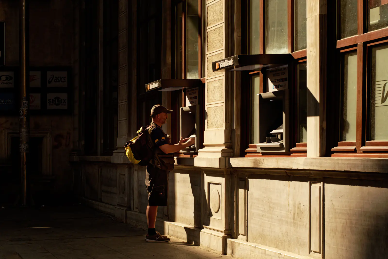 Traveler withdrawing cash from a street ATM in golden evening light